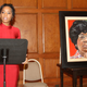Anika Noni Rose stands near a portrait of Shirley Chisholm.
Facebook